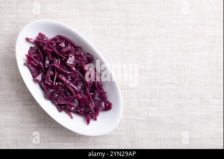 Braised red cabbage in a white bowl, with empty space for text. Traditional German side dish of intense purple color made of sliced cabbage. Stock Photo