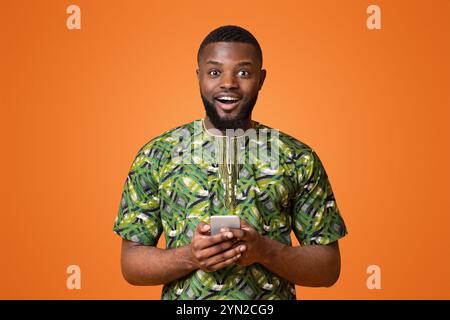 Excited black guy holding modern mobile phone Stock Photo