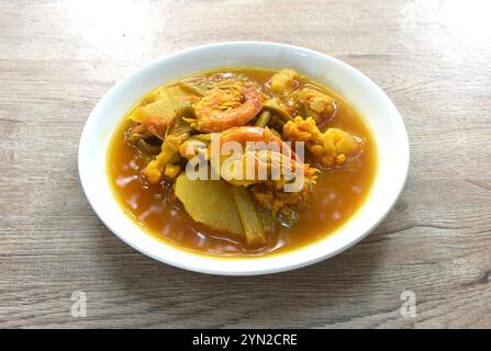 boiled shrimp and mixed vegetable in spicy and sour orange curry soup on plate Stock Photo