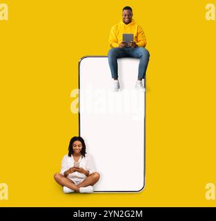 Couple sitting on white empty smartphone screen and using phones Stock Photo