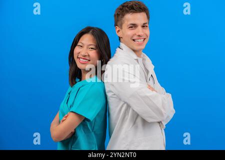 Smiling Medical Professionals Standing Back-to-Back on Blue Background Stock Photo