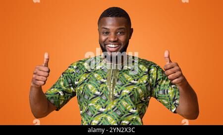 Happy black guy in green african shirt showing thumbs up Stock Photo