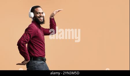 Smiling black guy enjoying music with headphones and dancing Stock Photo