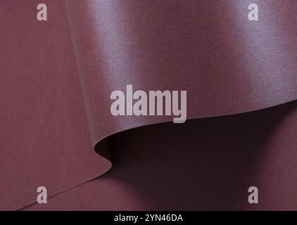 Burgundy metallic paper background with a shimmering, sleek surface and soft folds. Featuring a rich gradient and reflective sheen, it exudes elegant Stock Photo