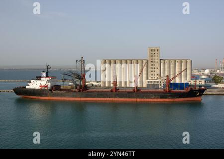 Cargo ship docked alongside grain silos in La Goulette, Tunisia. Stock Photo