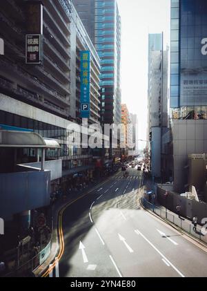 Sunny Urban Street in Hong Kong Framed by High-Rise Buildings and Shadows - Vibrant City Life Perspective Stock Photo