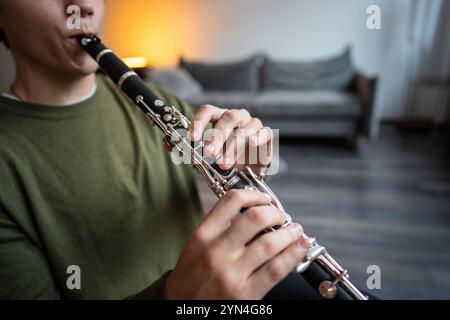 Clarinet player. Clarinetist hands playing flute woodwind music instrument at home, closeup view Stock Photo