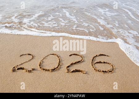 The inscription 2026 on the sand by the sea. Happy New Year. Stock Photo