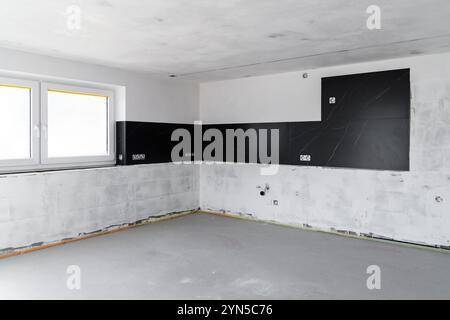 Modern Unfinished Kitchen Interior with Black Backsplash Tiles, Electrical Sockets Installed, and Walls Prepared for Renovation in Contemporary Home D Stock Photo