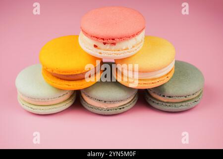 Multicolored macaroons desserts stacked in a pyramid. Yellow, green and pink macaroons are elegantly stacked in a slide, showcasing the taste and qual Stock Photo