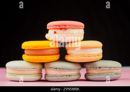 Multicolored macaroons desserts stacked in a pyramid. Yellow, green and pink macaroons are elegantly stacked in a slide, showcasing the taste and qual Stock Photo