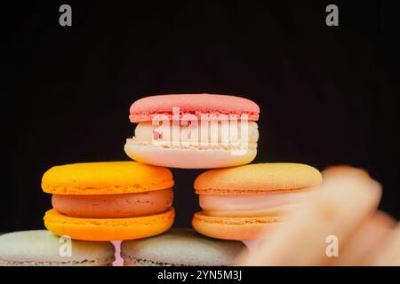 Multicolored macaroons desserts stacked in a pyramid. Yellow, green and pink macaroons are elegantly stacked in a slide, showcasing the taste and qual Stock Photo