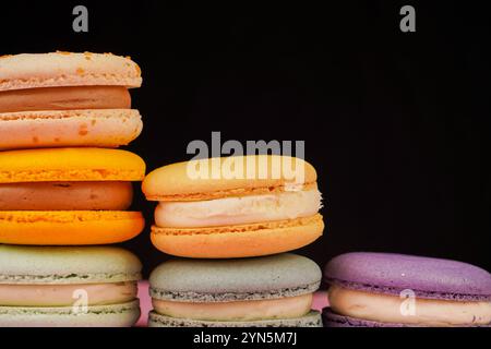 Multicolored macaroons desserts stacked in a pyramid. Yellow, green and pink macaroons are elegantly stacked in a slide, showcasing the taste and qual Stock Photo