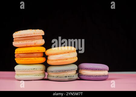 Multicolored macaroons desserts stacked in a pyramid. Yellow, green and pink macaroons are elegantly stacked in a slide, showcasing the taste and qual Stock Photo