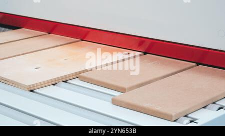 An industrial machine in a factory cuts and applies patterns to wooden panels for furniture production Stock Photo