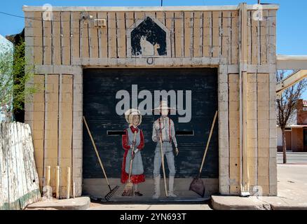 Mural painting on a garage door of a farmer man and woman with cats under a good luck horse shoe in rural New Mexico. Stock Photo