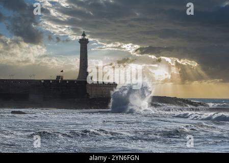 Scenic sunset over the atlantic ocean, a lighthouse at the shore of Morocco, waves break at the coast Stock Photo