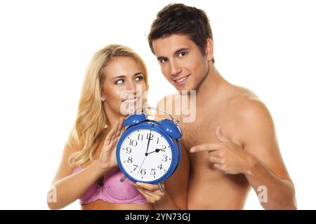 Time change, Clock change, Summer time, Winter time, Couple with alarm clock, Blonde woman, 25, 30, Young man, 25.30, Years, Couple studio shot, Feder Stock Photo