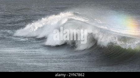 A breaking wave creating a rainbow, full frame, long size Stock Photo