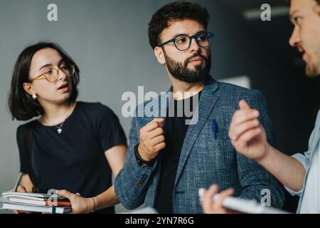 Engaged students conversing with professor in university corridor Stock Photo
