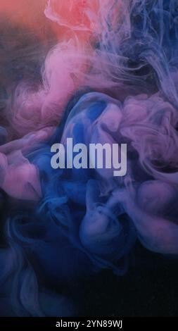 Oil painting. Draw together. Multicolored cosmetic powder. Blue pink liquid in blending flow on blurred gleaming orange abstract background. Stock Photo