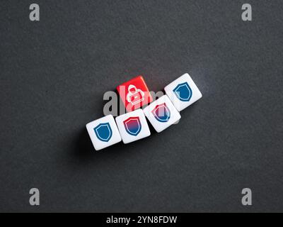 Cyber security and hacker attack concept. Red dice showing hacker icon surrounded by white dice with shield icons on dark background. Stock Photo