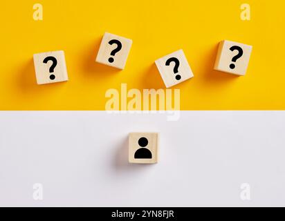 FAQ. Entering to the zone of uncertainty. Facing questions, doubt or problems. Question marks on wooden cubes on a yellow background facing a person i Stock Photo