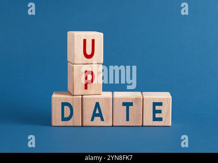 Wooden cubes spell update on blue background, symbolizing progress in business and technology. Stay current and adapt to succeed in digital age Stock Photo