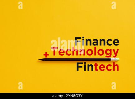 Black pencil underscoring the fintech equation of finance plus technology on a vibrant yellow background, representing innovation in financial technol Stock Photo