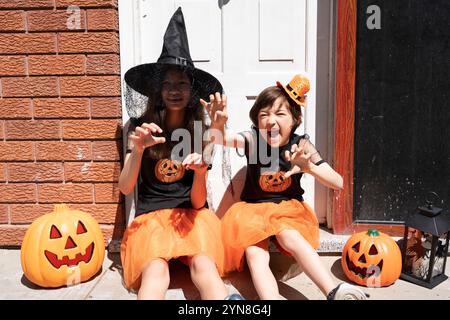 Two girls in Halloween costumes at the door of a house Stock Photo