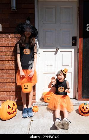 Two girls in Halloween costumes at the door of a house Stock Photo