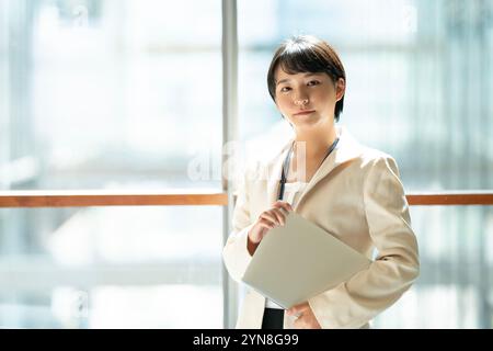 Woman standing inside a building holding a computer Stock Photo