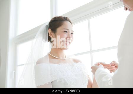 Smiling bride and groom during exchange of rings Stock Photo