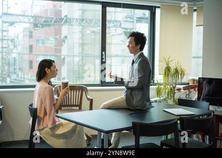 Man and woman at work in office talking by window Stock Photo