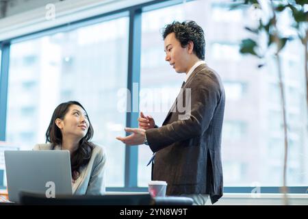 Smiling man in his 20s explaining to woman Stock Photo