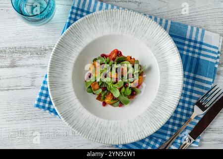 Purslane salad with tomatoes, pomegranate and crispy dough served on a white porcelain plate Stock Photo