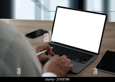 man working on laptop computer with blank screen laptop computer mock up in office Stock Photo