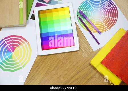 Designer's workplace with tablet, palettes and stationery on wooden table, flat lay Stock Photo