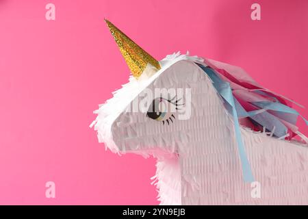 Bright pinata in shape of unicorn on pink background Stock Photo