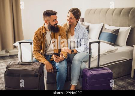 Young happy couple is on vacation. Tourists arrived in hotel room with their suitcases. Stock Photo