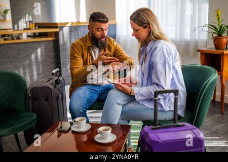 Young couple is going on vacation. Tourists sitting at airport cafe because of delayed flight. Stock Photo