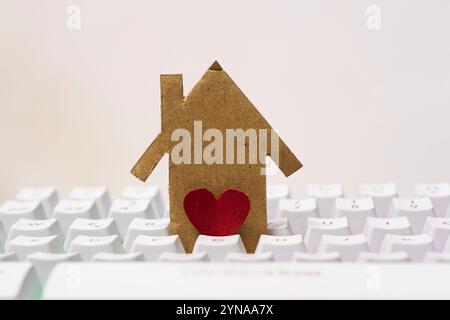 Paper house with red heart on white keyboard background. Concept of love for home, real estate, mortgage, loan, mortgage. Stock Photo