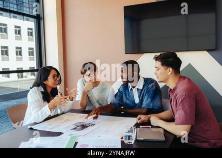 A diverse study group in intense discussion, collaborating over notes and tablet in a modern setting. Engaged students working together. Stock Photo
