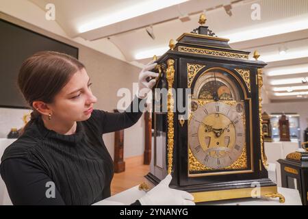 London, UK. 25 November 2024  An art handler with a fine mid 18th century brass mounted ebonised 12 tune musical table clock. Estimate: £7,000-£10,000.Preview of Bonhams Fine Clocks Sale .as part of Classics weeks. The sale takes place at Bonhams New Bond Street on 26 November. Credit .Amer Ghazzal/Alamy Live News Stock Photo