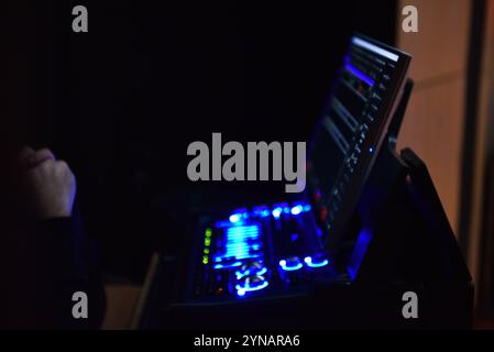 Close up hands shot of sound engineer using mixing console, remote control for adjusting sound, audio mixer blurred view Stock Photo