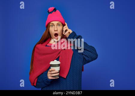 A young man with bright red hair chatters on the phone while sipping coffee. Stock Photo