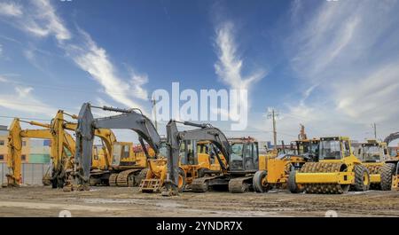 Various heavy construction vehicles, such as excavators, diggers, earthmovers, and bulldozers, are stationed at a construction site throughout the win Stock Photo