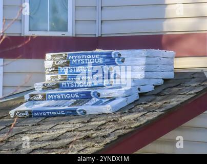 Calgary, Alberta, Canada. Mar 17, 2024. Multiple bundles of Tone Black Fiberglass Roofing Shingles positioned atop a house awaiting installation as pa Stock Photo