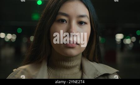 Close up portrait pensive serious Asian chinese ethnic woman young girl businesswoman female in dark parking city unhappy customer car owner client Stock Photo