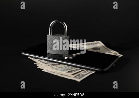 Padlock with money, mobile phone and key on black background Stock Photo